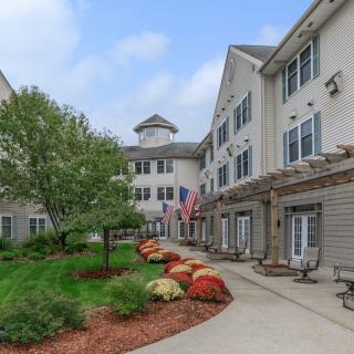 A well-maintained building with a landscaped pathway, featuring colorful flowers and national flags.
