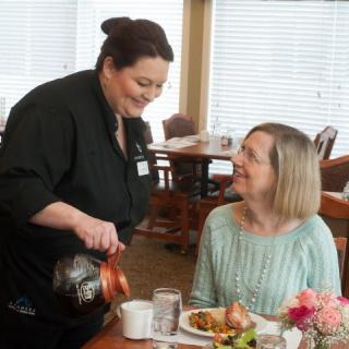A waitress pours coffee for a customer in a restaurant setting.