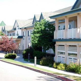 A sunny view of a residential building with trees lining the sidewalk.