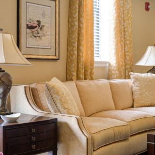 A cozy living room with a beige sofa, elegant lamps, and golden curtains.