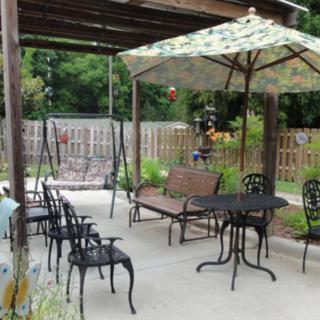 A cozy outdoor patio area with various seating options, including a swing bench and tables under a pergola and umbrella.