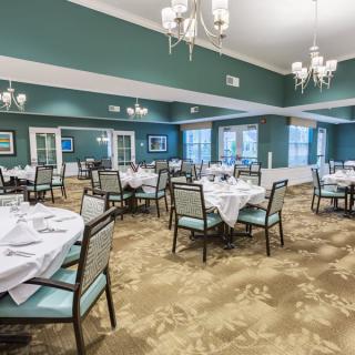 An elegant dining room with neatly set tables and chandeliers, creating a formal atmosphere.