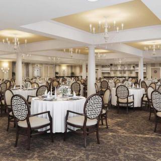 An elegantly decorated banquet hall with round tables and chandeliers.
