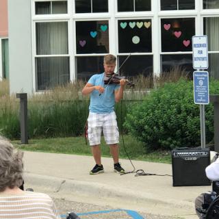 A young musician performing on the street with a violin, entertaining an outdoor audience.
