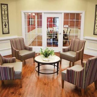 A cozy seating area with four striped armchairs around a coffee table on a hardwood floor.