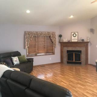 A cozy living room featuring a fireplace, sofas, and a window with wooden blinds.
