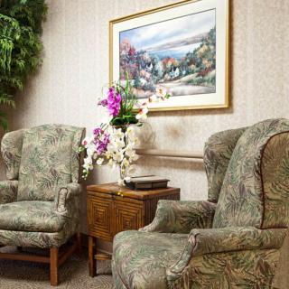 A cozy waiting room with floral chairs and a framed painting.