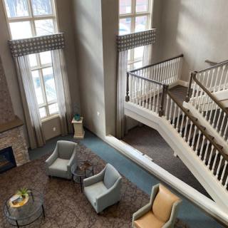 A spacious lobby area featuring a modern staircase, comfortable seating, and large windows.