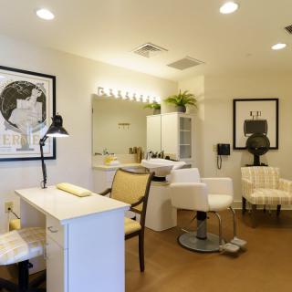 A modern and stylish hair salon interior featuring seating, mirrors, and artwork on the walls.