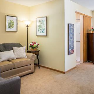 A cozy living room with a sofa, floor lamp, and decorative artwork on the walls.