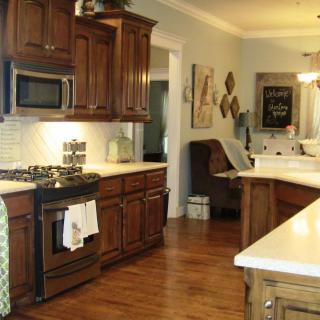 A cozy kitchen with wooden cabinets, featuring a stove and microwave.