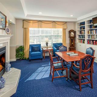 A cozy living room with a fireplace, armchairs, and a dining table surrounded by bookshelves.