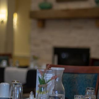 A cozy restaurant interior with a neatly set dining table near a fireplace.