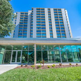 A modern hotel showcasing a sleek glass facade and well-maintained landscaping.