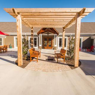 A sunny outdoor patio featuring a wooden pergola and seating area.