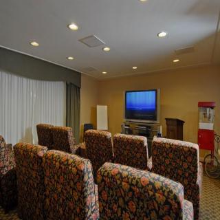 A cozy home theater setup with rows of upholstered seating facing a large TV, complete with a popcorn machine in the corner.
