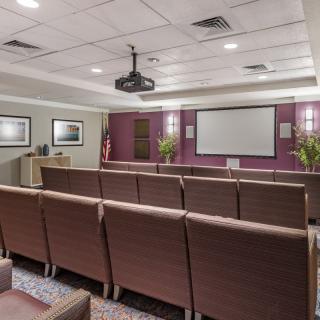 A small indoor theater with multiple rows of seating and a projector screen.
