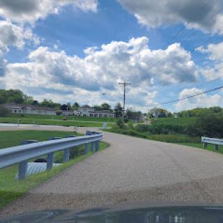 A winding road through a scenic countryside landscape under a partly cloudy sky.