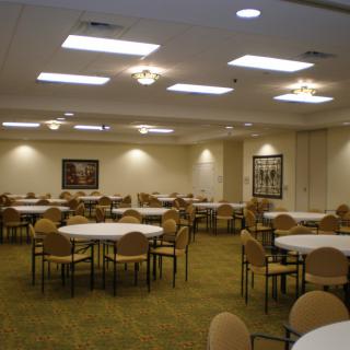 An empty banquet hall set up with round tables and chairs, ready for an event.