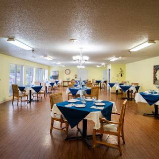 A spacious dining area featuring blue tablecloths and wooden chairs, designed for a casual dining experience.