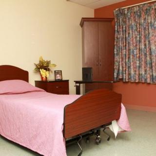 A cozy bedroom with a single bed, pink bedding, and wooden furniture.