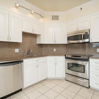 A modern kitchen featuring white cabinetry and stainless steel appliances.