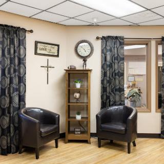 A cozy waiting area featuring black chairs, decorative curtains, and a display cabinet.