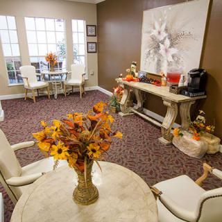 A cozy living room with elegant furnishings, floral decorations, and large windows.
