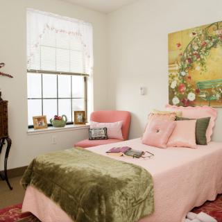 A cozy bedroom featuring pink bedding, elegant decor, and a large artwork on the wall.