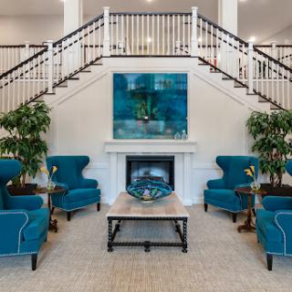 A stylish lobby featuring cozy teal armchairs, a modern fireplace, and an elegant staircase.