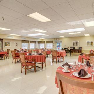 A spacious dining area featuring round tables with red tablecloths and decorative place settings.