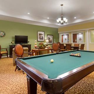 A well-furnished game room featuring a pool table and comfortable seating areas.