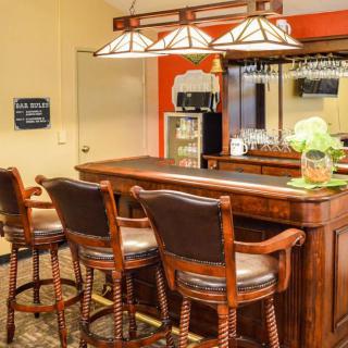 A cozy indoor bar setup with a wooden counter and high chairs.