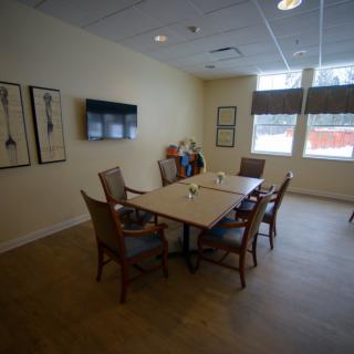 A conference room with a meeting table, chairs, and a television on the wall.