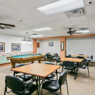A spacious recreational room featuring a pool table and multiple seating arrangements for group activities.