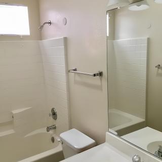 A clean, minimalistic bathroom with a shower-bathtub combo and a large mirror.