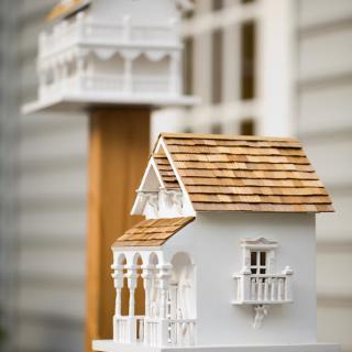 A detailed wooden birdhouse with intricate design and shingled roof.