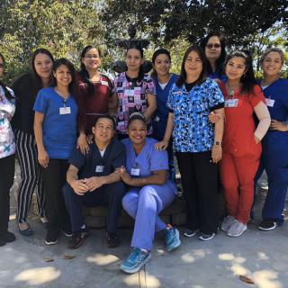 A group of healthcare workers posing together outdoors in their uniforms.
