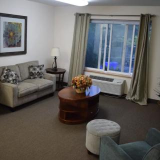A cozy living room with a sofa, coffee table, and large window with curtains.