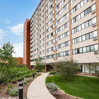 A modern apartment building surrounded by landscaped gardens and pathways.