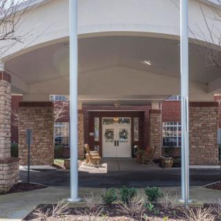 The entrance of a building with brick walls and columns under an awning.