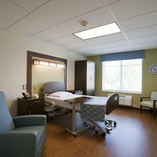 A modern hospital room with a patient bed and seating area.