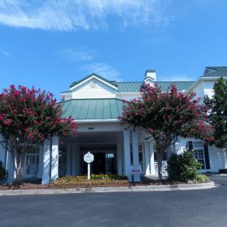 A view of a hotel entrance with trees and a clear blue sky.