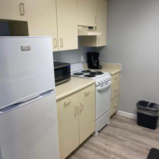 A compact kitchen with essential appliances including a refrigerator, microwave, stove, and coffee maker.