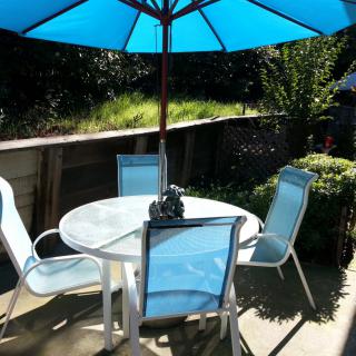 A patio set with a table, chairs, and an umbrella in a garden setting.