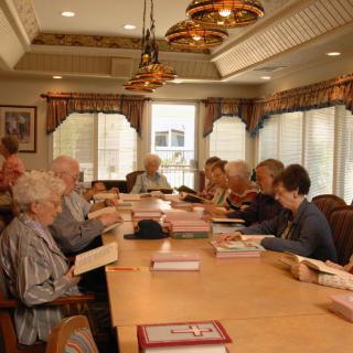 A group of senior citizens engaged in a book club discussion around a large table.