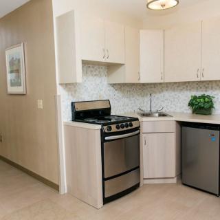 A modern kitchen with stainless steel appliances, light cabinetry, and a tiled backsplash.