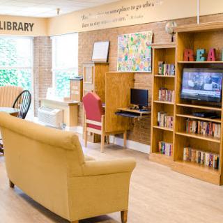 A cozy library space featuring comfortable seating and bookshelves filled with a variety of books.