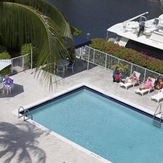 A serene outdoor swimming pool area with lounge chairs and a view of the waterfront.