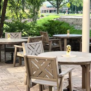 A tranquil patio with wooden tables and chairs surrounded by lush greenery.